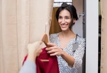 Customer being handed clothes in fitting room