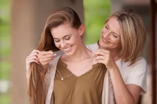 Mother gifting daughter with necklace