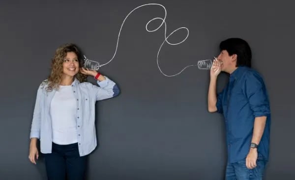 People talking and listening through tin cans with a string